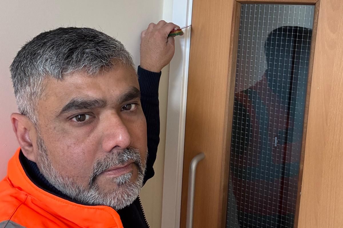 Naseem Jana measuring a fire door gap with a gap gauge during a fire door inspection in Bedford